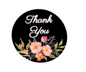 Close-up of a round black Thank You sticker with floral design and white cursive text