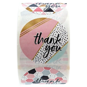 Macro detail of round geometric thank you stickers on a roll with gold and pink patterns