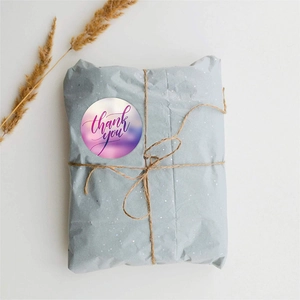 Detailed view of round purple thank you sticker applied on a gift wrap with twine