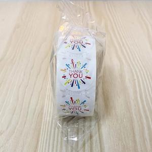 Detail of colorful THANK YOU round sealing stickers roll on wooden background texture