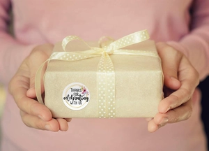 Detail of floral Thank You sticker on brown kraft gift box with cream polka dot ribbon