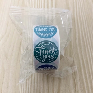 Macro shot of blue Thank You label roll with leaf patterns in transparent plastic wrap