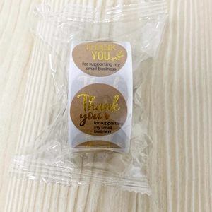 Macro view of gold foil Thank You stickers on kraft paper roll for small business