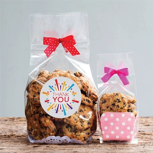 Roll of thank you stickers on clear cookie packaging with red and pink bows