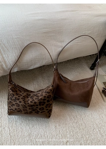 Detail showing retro leopard print and matte brown leather hobo bags in soft home setting