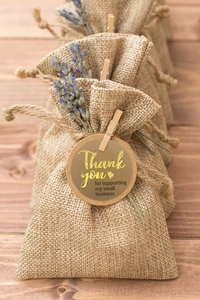Linen drawstring gift bags with wooden clips and dried lavender on a rustic wooden background