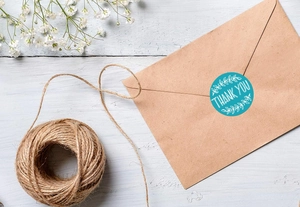 Teal round thank you sticker seal on kraft envelope with decorative leaves and hemp rope