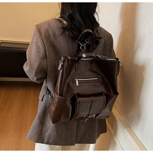 Détail du grand sac à dos vintage en cuir ciré porté par un mannequin en extérieur