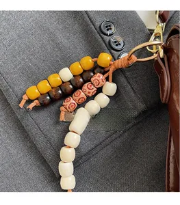 Detail of colorful beaded charm with wood beads and woven cord on a luxury bag