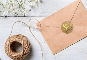 Close-up of golden foil Thank You sticker on a brown kraft envelope for small business packaging