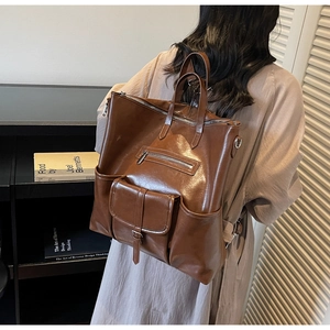 Détail du sac à dos vintage en cuir ciré marron montrant la texture et les poches