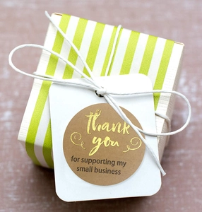 Detail of white gift tag with gold foil 'thank you' sticker and white string