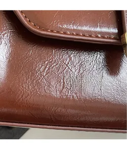 Detail of brown oil wax leather texture with neat stitching and gold hardware accents