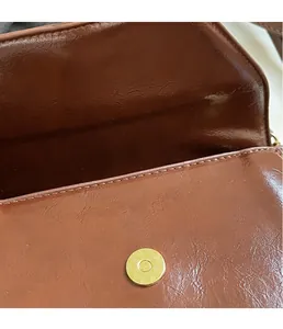 Close-up of the metal magnetic buckle and brown textured leather on this fashion handbag