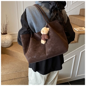 Détail d'un grand sac cabas en daim marron avec un joli porte-clés ours en peluche
