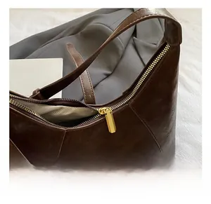 Close-up of golden zipper and lychee pattern leather on dark brown shoulder bag