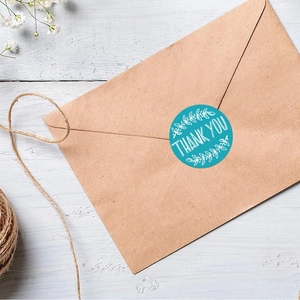 Blue Thank You round seal stickers on kraft envelope with flowers and wood backdrop