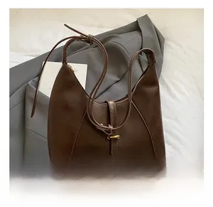 Detailed close-up of a dark brown faux leather shoulder bag with a buckle strap and zipper