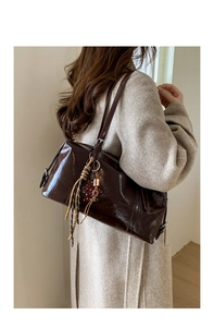Detail of dark brown wax leather handbag with leopard print charm and metal buckle