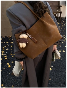 Vue détaillée d'un sac cabas en daim marron avec pendentif ours dans un décor d'automne