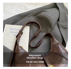 Detail of adjustable leather strap and golden buckle on dark brown polished hobo bag