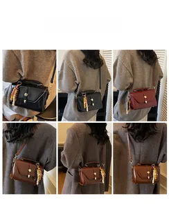 Detail view of stylish crossbody bags in black, burgundy and brown with tassel charms