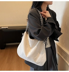 Detail of a large off-white canvas tote bag featuring stylish striped braided rope straps