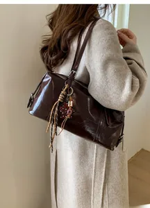 Detail of dark brown glossy leather handbag with braided cord and leopard star charm