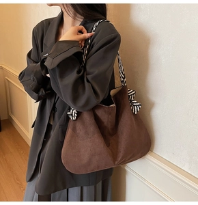 Brown suede tote bag with black and white striped shoulder strap shown on model