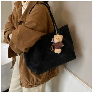 Gros plan d'un grand sac cabas en daim noir avec un joli pendentif en forme d'ourson
