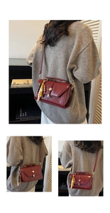 Detail of burgundy textured leather bag with gold hardware and colorful beaded charm