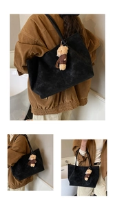 Détail du sac cabas en daim noir avec coutures décoratives et un petit ours en peluche