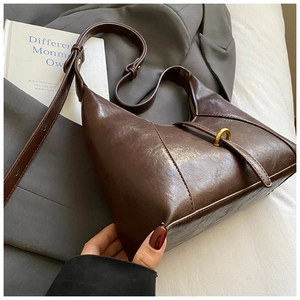Detail of dark brown leather shoulder bag with vintage gold ring buckle and strap