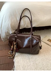 Detail of vintage dark brown wax leather pillow bag with stylish decorative charms