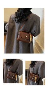 Brown glossy small crossbody bag with colorful bead charm on a grey tweed coat