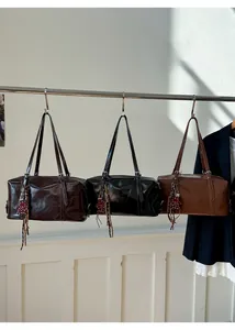 Close-up of Boston hand bags in dark coffee, black and caramel brown with tassel charms