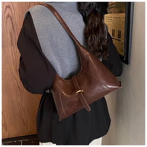 Detail of dark brown hobo shoulder bag with glossy finish and golden metal D-ring buckle