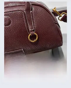 Dettaglio borsa Boston in pelle martellata bordeaux con cuciture bianche e finiture oro