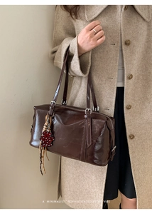 Detail of vintage oil wax leather boston bag in brown with heart bear charm and metal buckle