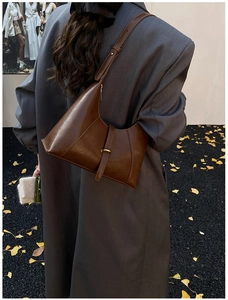 Detailed texture of brown soft leather baguette bag with elegant golden buckle hardware