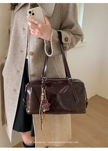 Deep brown oil wax leather tote bag with bear charm shown in a minimalist outfit