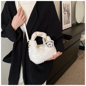 Détail du sac à main en peluche blanche avec poignée plissée et charmant ours suspendu