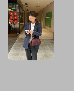 Borsa Boston bordeaux in pelle con tracolla regolabile indossata da una modella