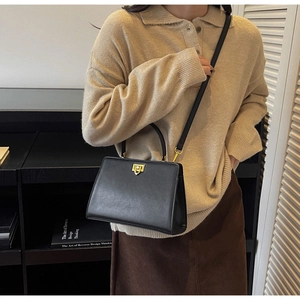 Detail of a black vintage handbag with a gold twist lock on a modern lifestyle background