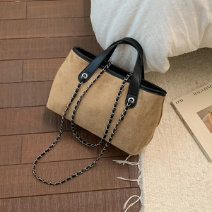 Detail of vintage brown suede tote bag with black leather trim and silver chain strap