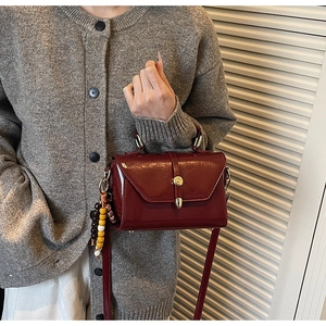 Detail view of burgundy oil-wax leather shoulder bag with retro bead pendant