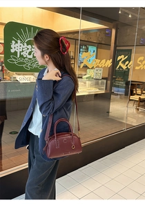 Vista lifestyle di una borsa bowling in pelle bordeaux con cuciture bianche a contrasto
