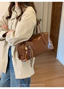 Close-up of retro brown oil wax leather pillow bag with minimalist metal zipper and charm
