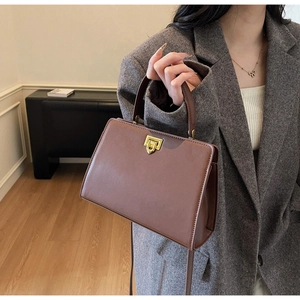 Retro large brown tote bag with gold lock shown on model wearing grey blazer coat