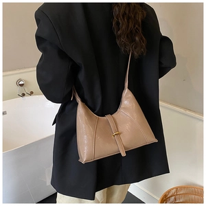Detail of a khaki faux leather hobo bag with gold metal buckle shown on shoulder